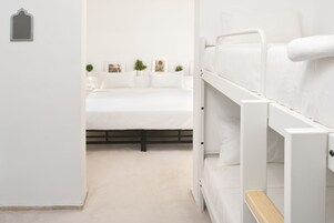 Un dormitorio con una cama litera, una cama individual y una mesita de noche.