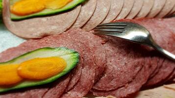 Una bandeja de carne en rodajas con rebanadas de aguacate encima.