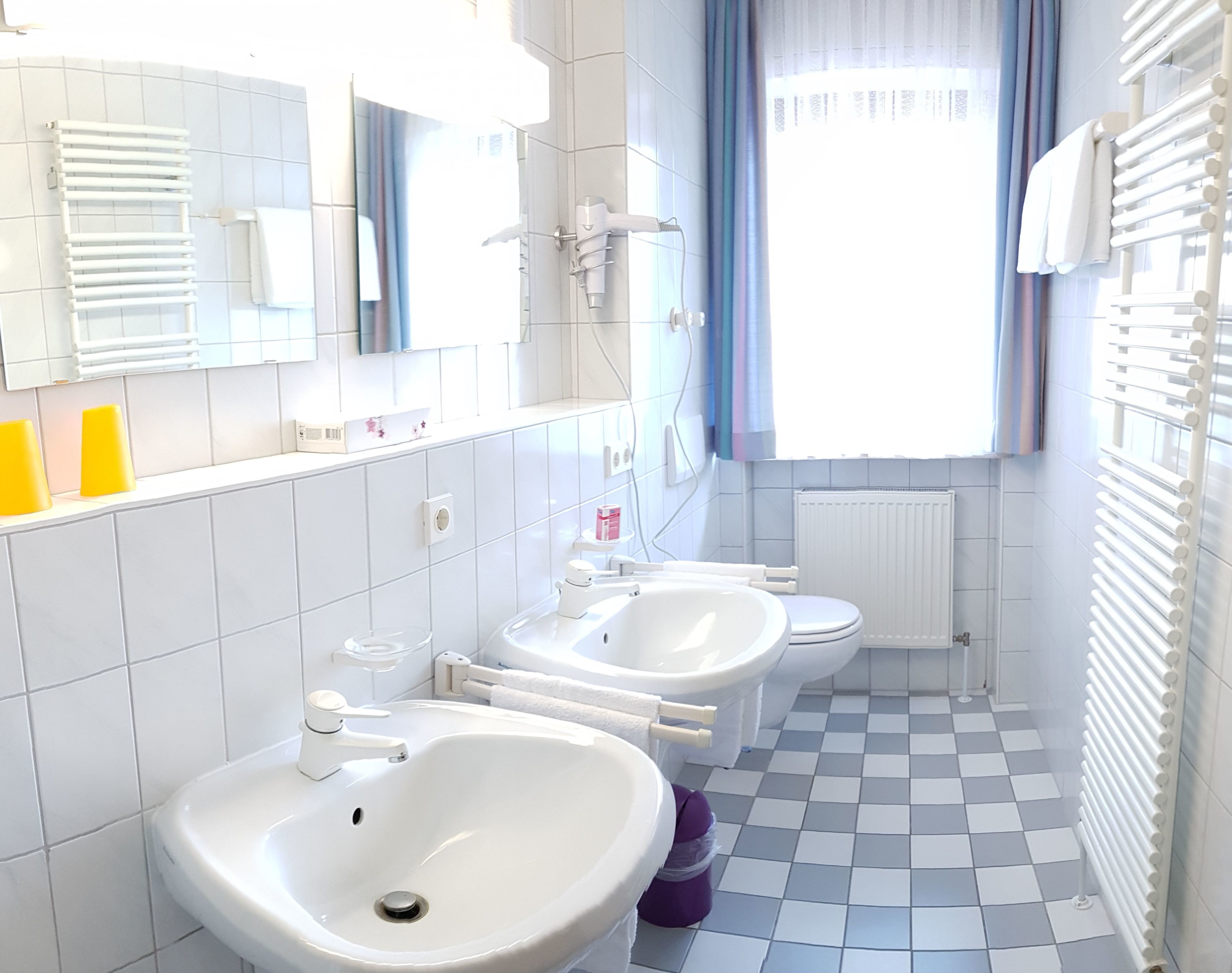 Une salle de bain moderne avec deux lavabos, des toilettes et un radiateur.