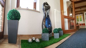 A modern interior with a sculpture, potted plants, and a tiled floor. - Kurhotel Anders (Bad Fuessing)