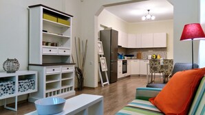 Una sala moderna con un sofá, una consola blanca y una cocina al fondo.