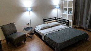 Un dormitorio pequeño y ordenado, con cama, mesitas de noche, una silla y un armario.