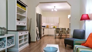 Una sala de estar moderna con un sofá, un comedor con mesa y sillas, una cocina con armarios y electrodomésticos, y un pasillo que lleva a otra habitación.