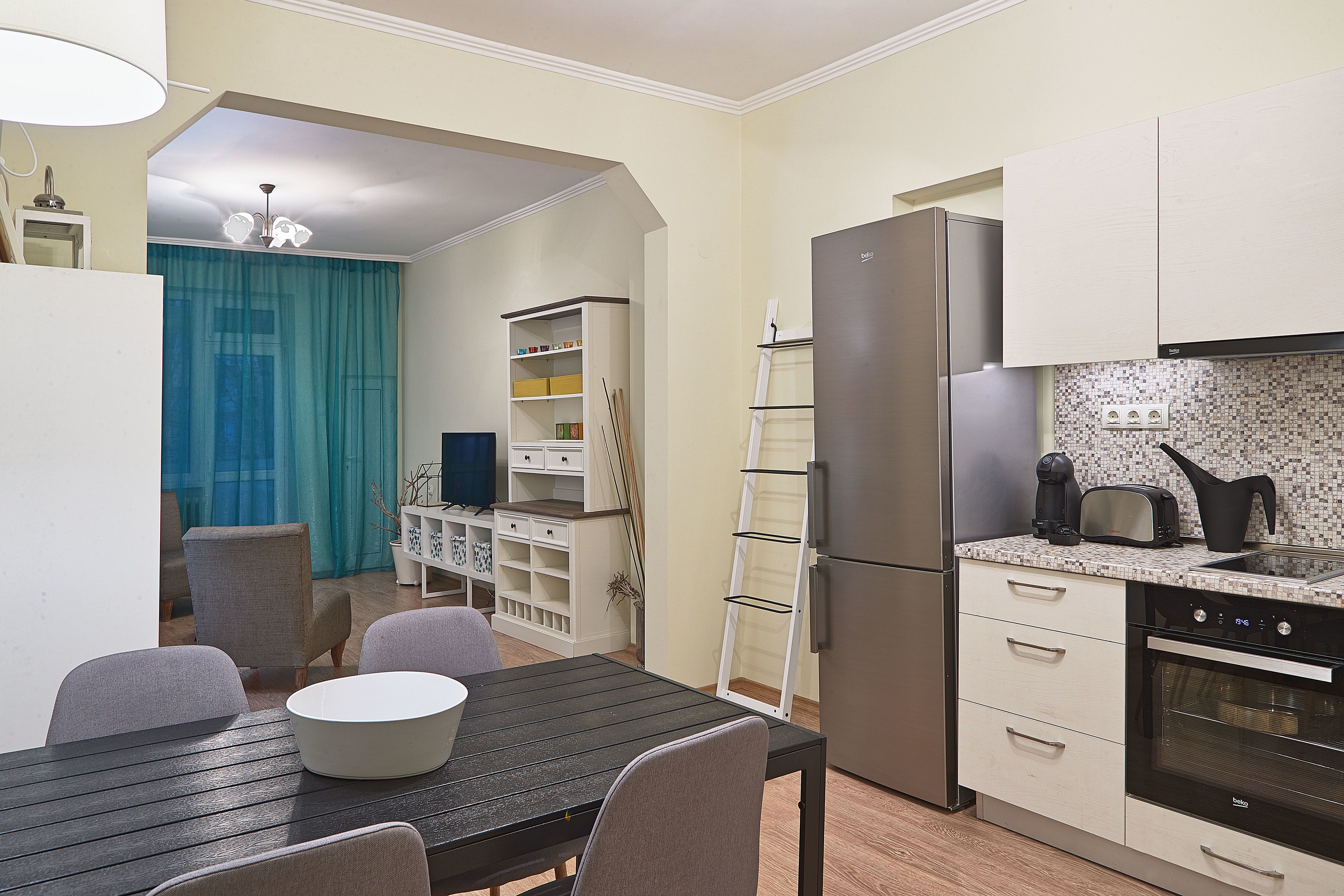 A compact kitchen with a refrigerator, stove, and a dining area with a table and chairs.