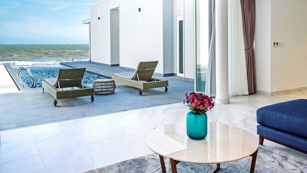 Habitación de hotel moderna con balcón con vistas al mar, una mesa redonda y un sofá.
