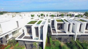 Un complejo residencial moderno con distribución enrejada, jardines en la azotea y vista al mar.