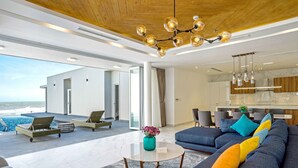 Una sala moderna con un sofá grande, una mesa de centro y vista al océano.
