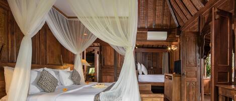 A room with a bed under a canopy, wooden walls, a ceiling fan, and a television on a wooden cabinet.