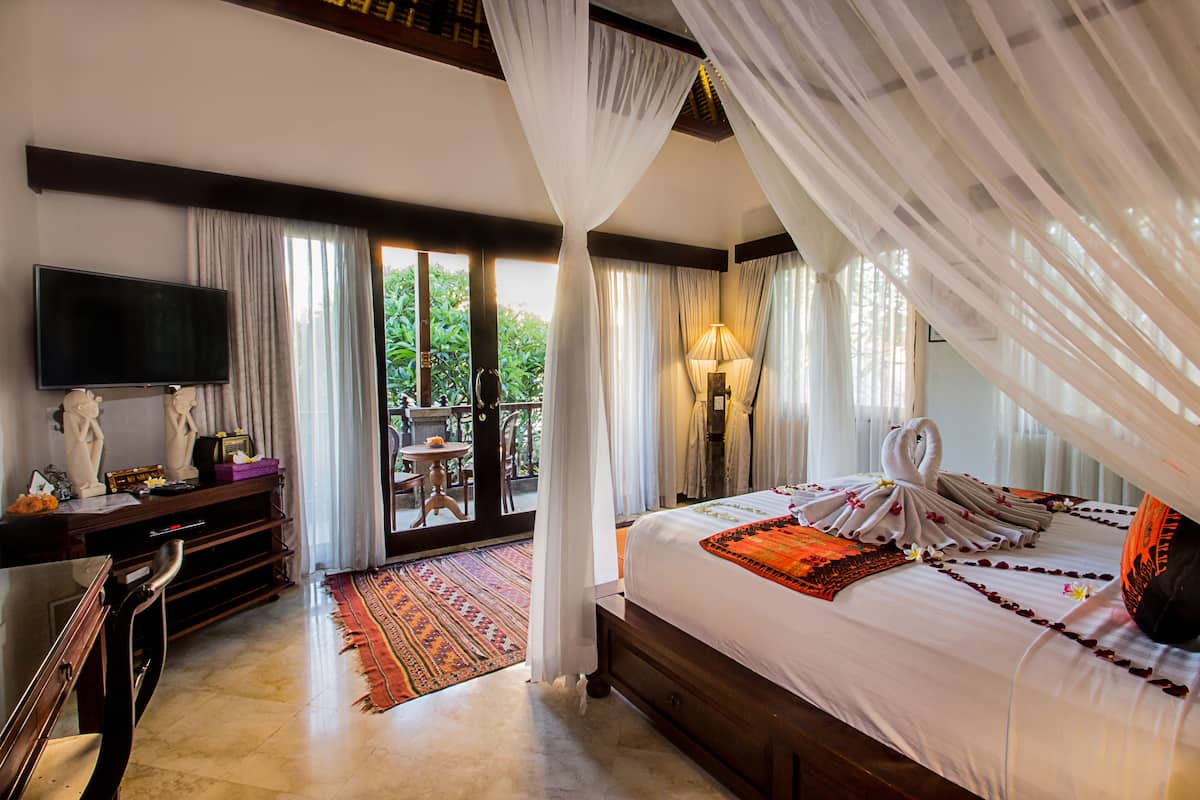 Une chambre d’hôtel avec un grand lit, une télévision, un bureau et un balcon donnant sur un espace verdoyant.