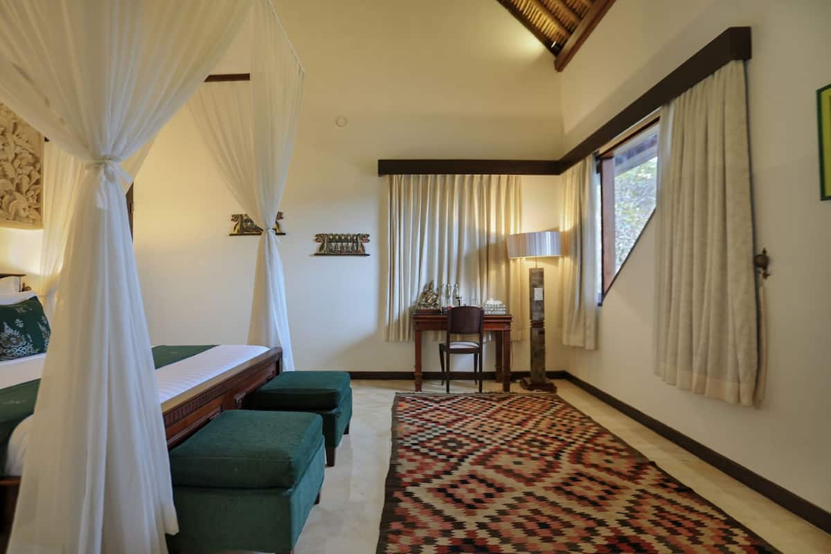 Une pièce comprenant un lit, des poufs verts, un tapis à motifs, un bureau avec une chaise et une fenêtre avec des rideaux.