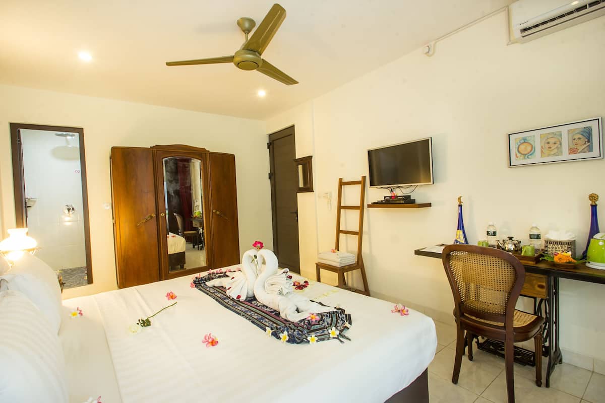 Une chambre d’hôtel équipée d’un lit, d’un bureau, d’une chaise, d’une télévision et d’un ventilateur de plafond.