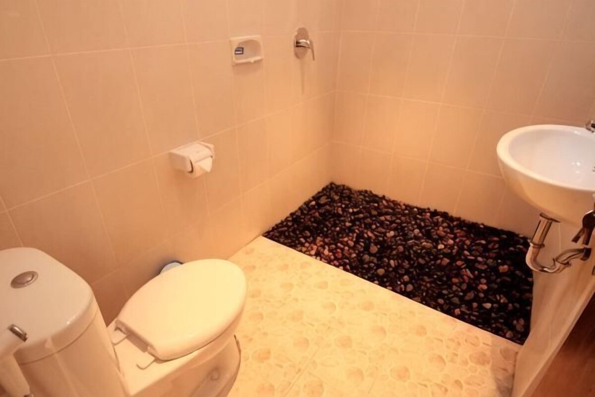 Une salle de bain comprenant des toilettes, un lavabo et un petit espace recouvert de galets.