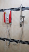 Boxe de chuveiro com painel de controle e chuveiro manual fixado em parede revestida com azulejos.