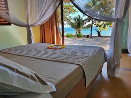 A bed with a view of a beach and ocean.
