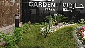 Une enseigne pour l’hôtel Garden Plaza, au design moderne, avec un logo et un texte dans plusieurs langues.