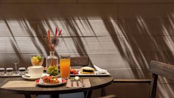 A dining table set with a meal, including a sandwich, a glass of orange juice, and a cup of coffee.
