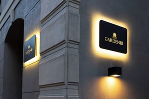 Letreros iluminados en la fachada de un edificio, incluyendo uno que dice 'GARDEN18'.