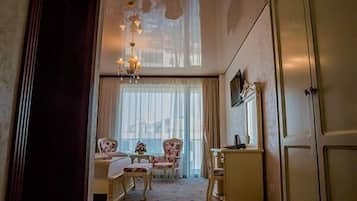 A room with a large window, a chandelier, a desk, and a chair.