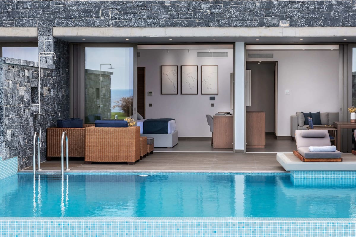 A modern pool area with a stone wall, a lounge chair, and a sofa.