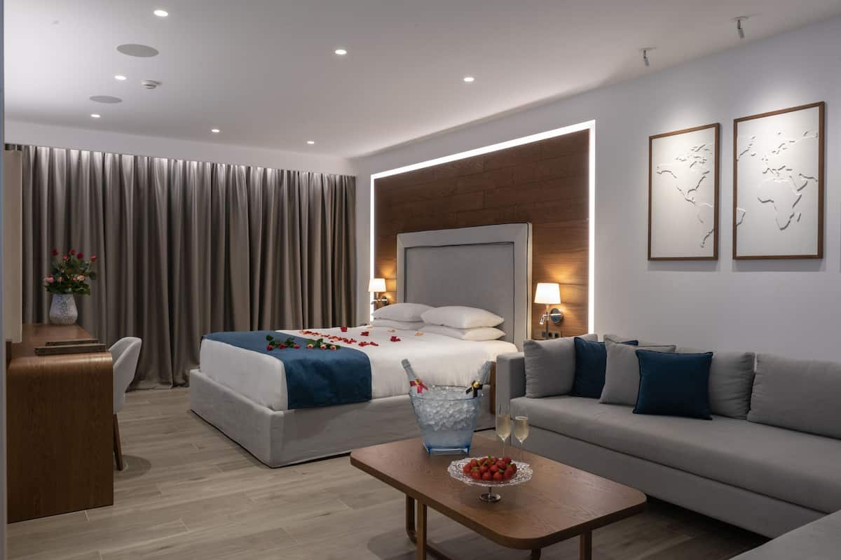 A modern hotel room with a bed, a sofa, a desk, and a coffee table.