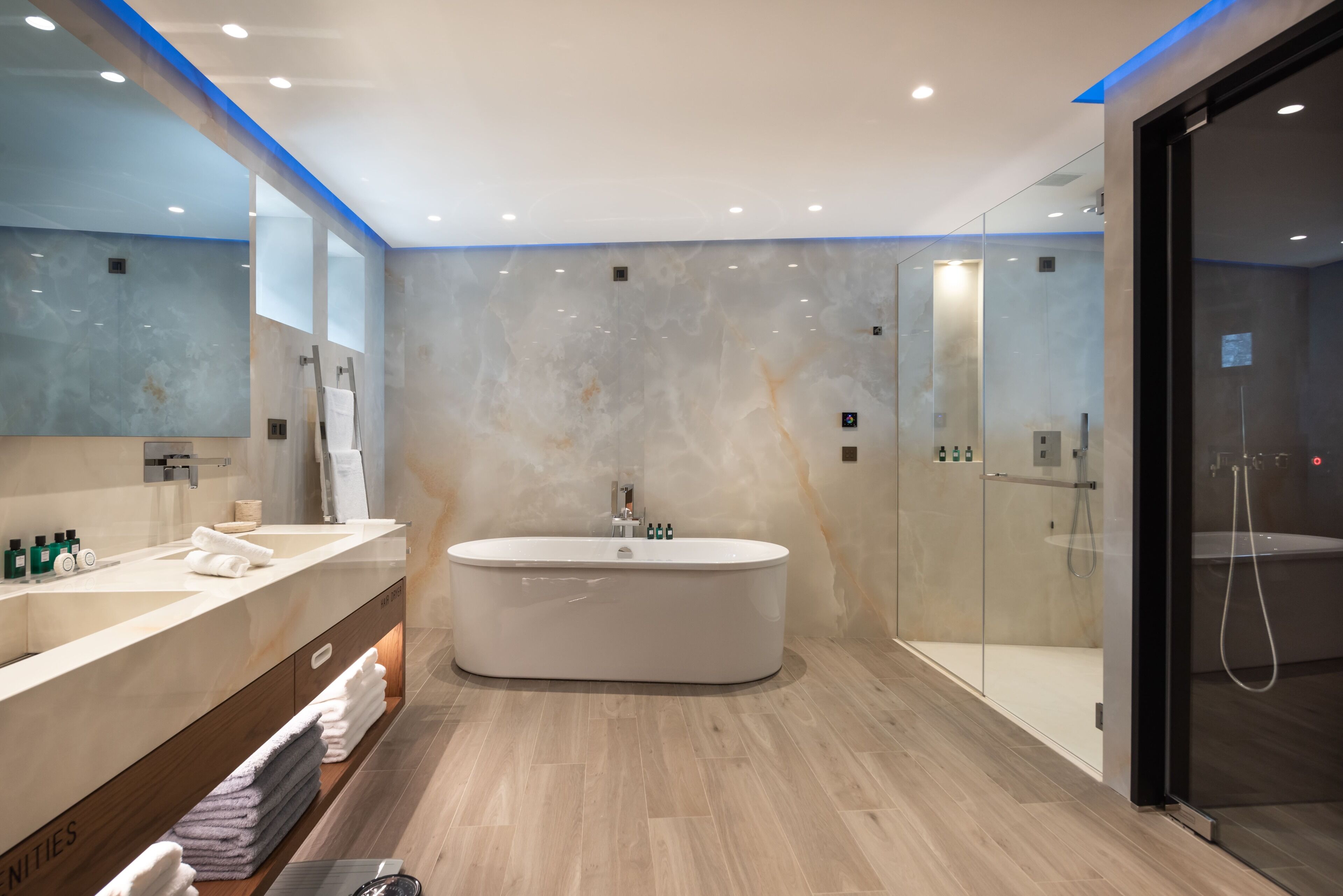 Un baño moderno con una bañera grande, un tocador con espejo y una cabina de ducha de vidrio.