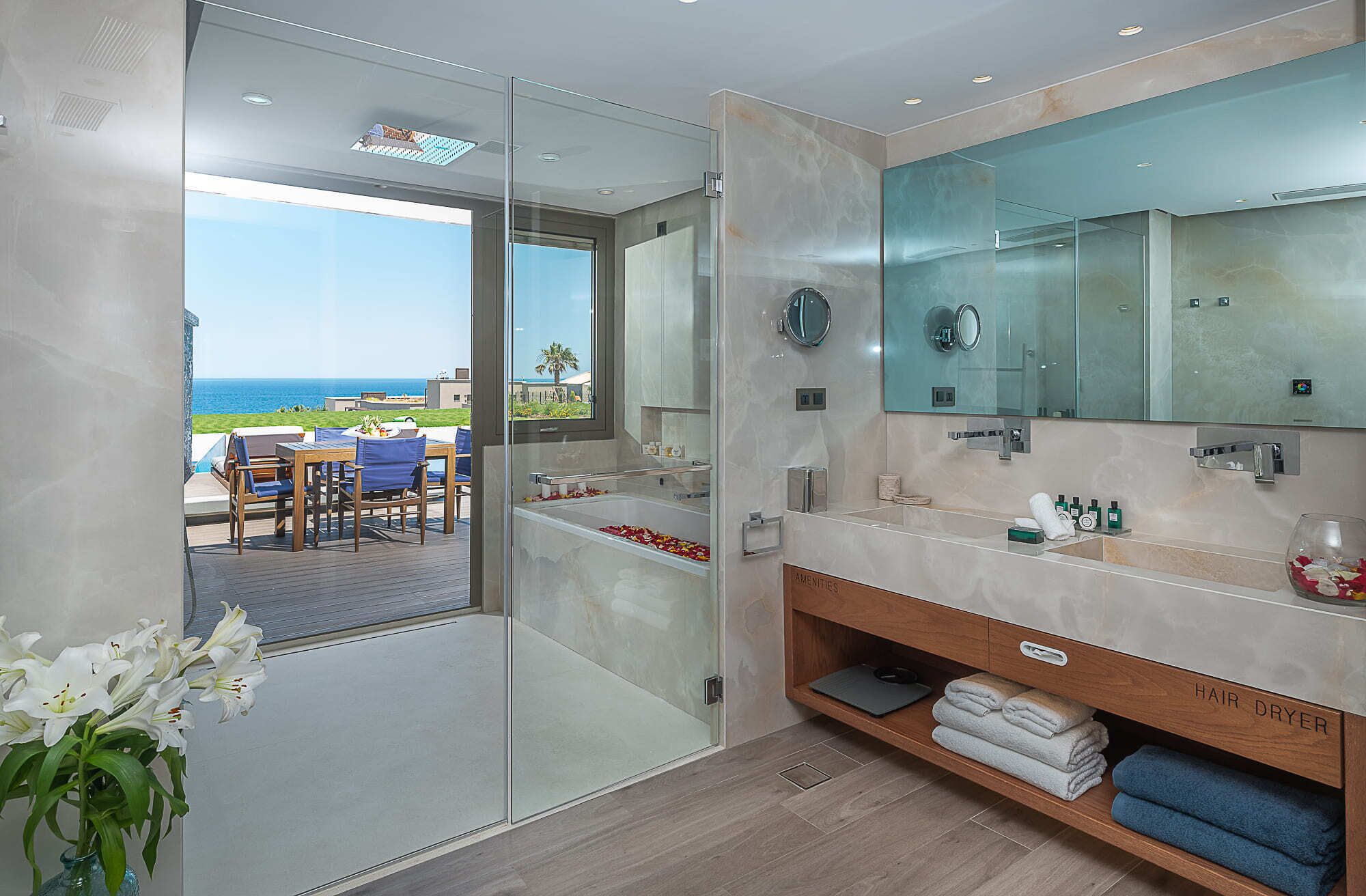 A modern bathroom with a large mirror, a hair dryer, and a view of the ocean.
