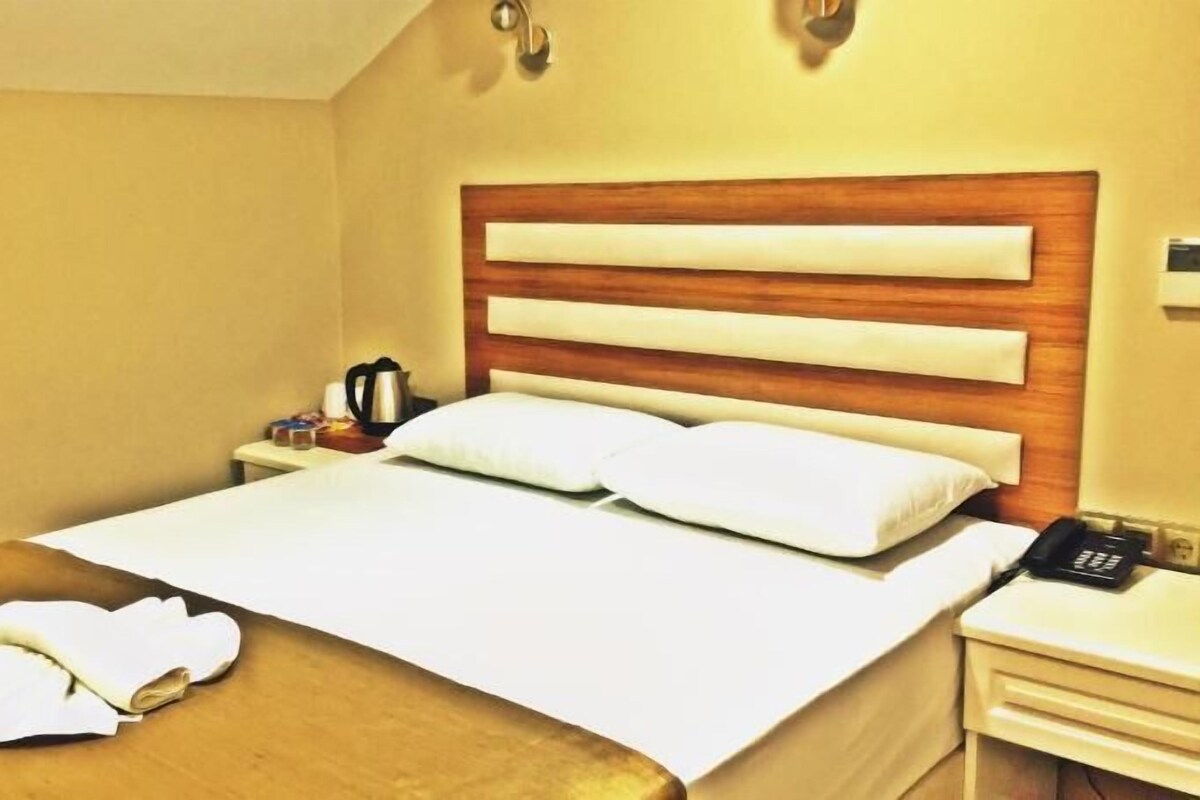 Una habitación de hotel con una cama, una mesita de noche con lámpara y un teléfono.