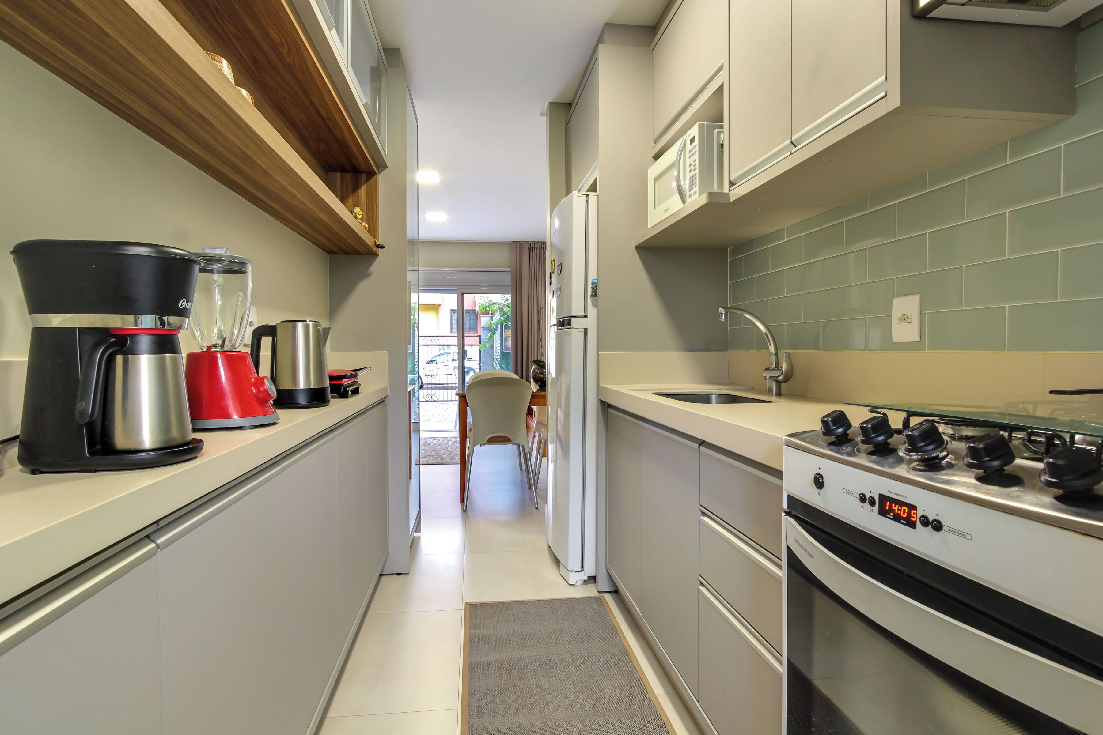 Cucina piccola con piano cottura, forno a microonde e macchina da caffè.