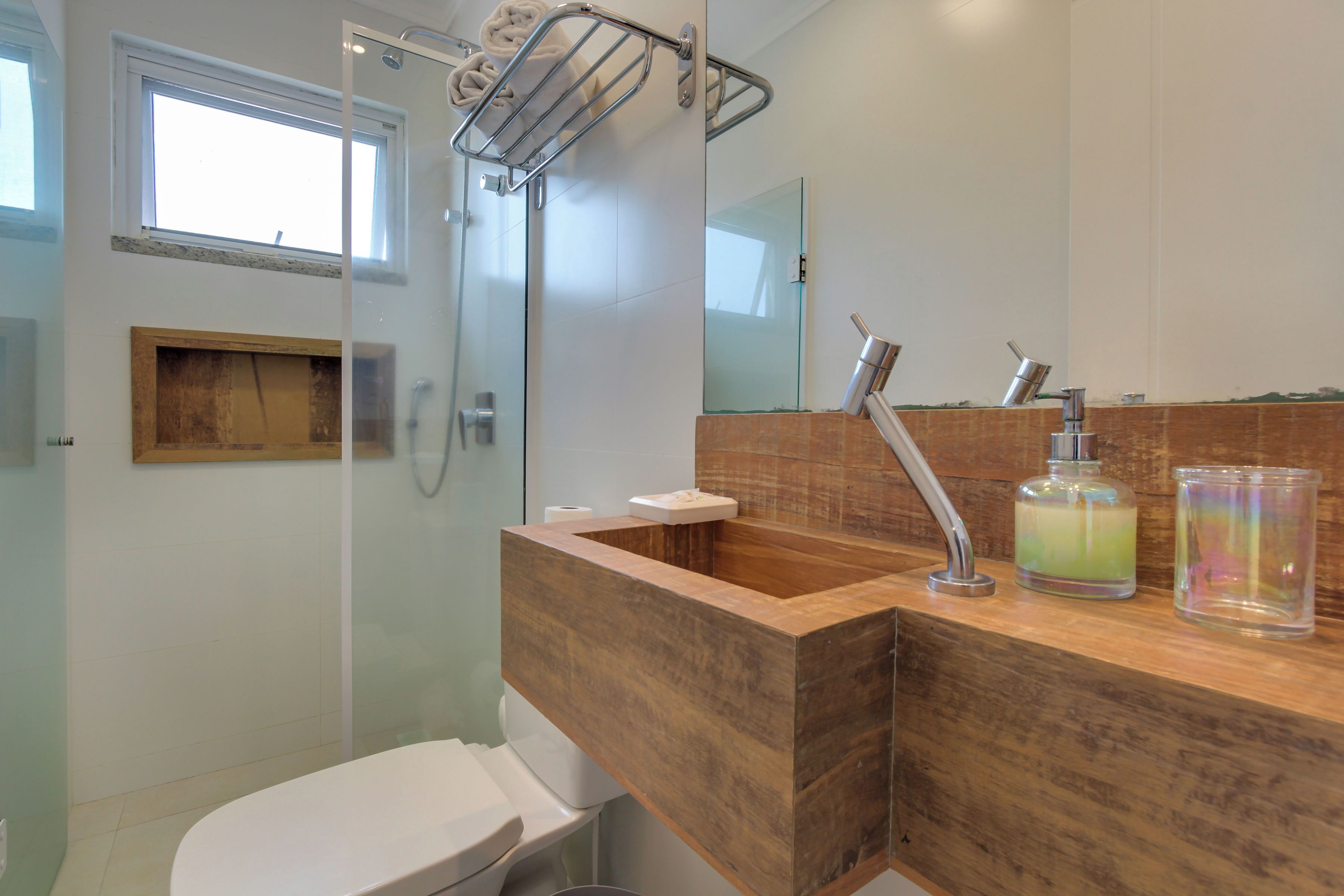 A modern bathroom with a glass shower enclosure, a wooden vanity, a toilet, and a mirror above the sink.