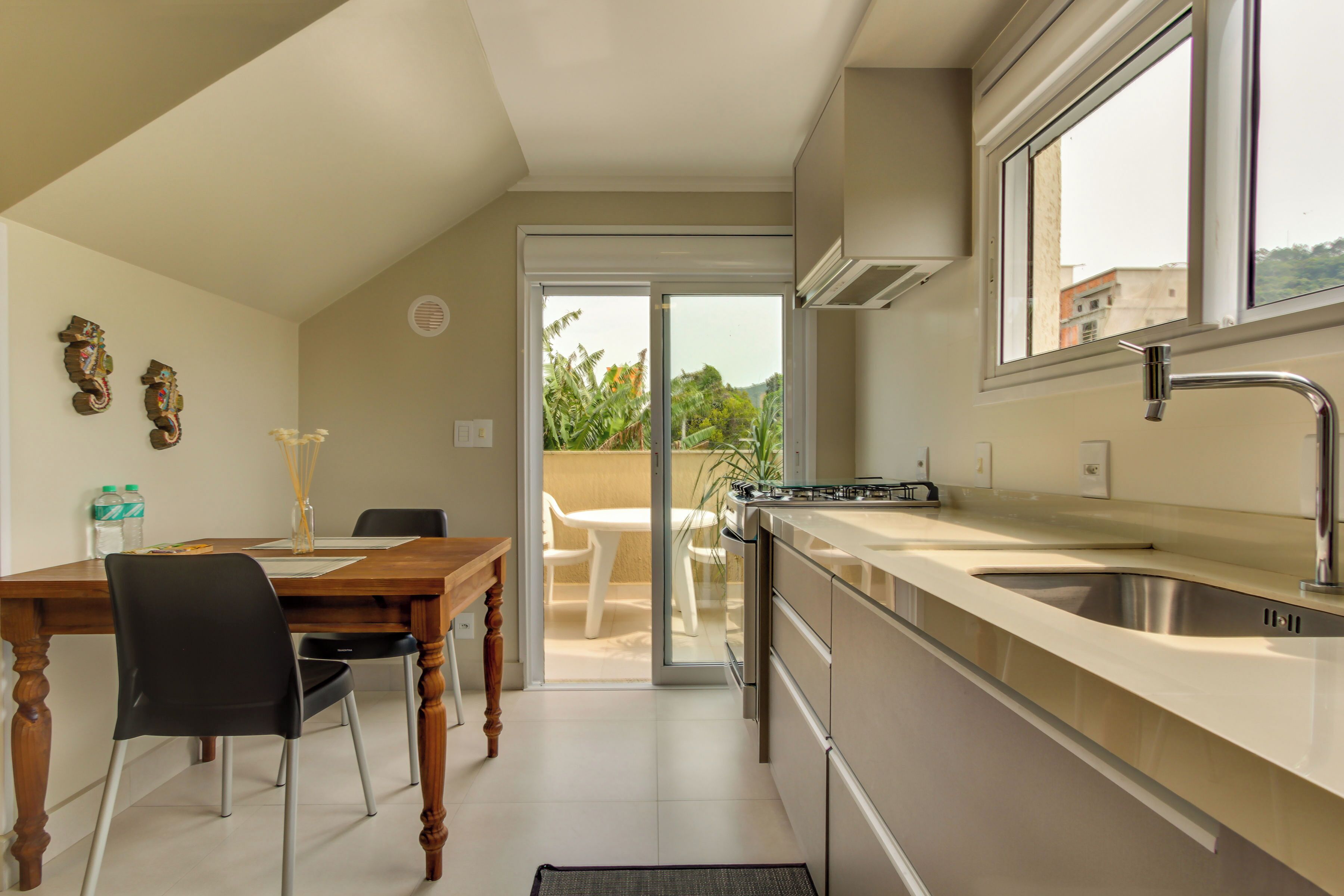 Una cocina moderna con un ventanal grande, un comedor con mesa y sillas, y vistas al exterior.