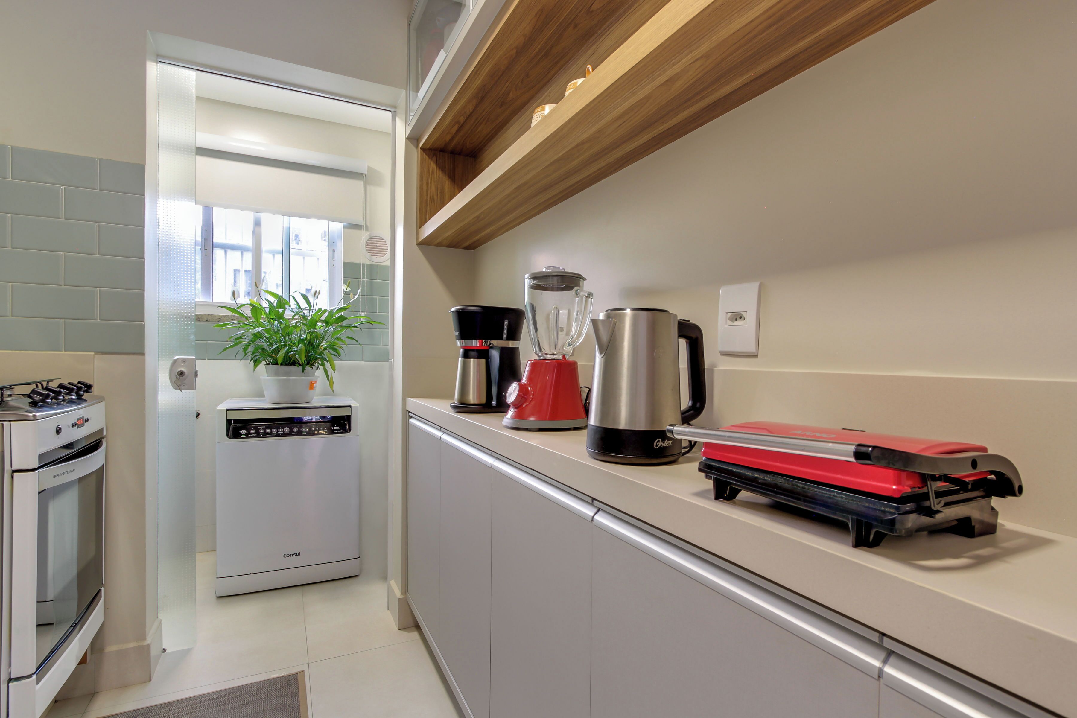 A modern kitchen with a dishwasher, a coffee maker, a kettle, and a red appliance on the counter.