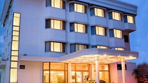 Een meerhoog hotel met een moderne gevel, grote ramen en een overdekt entreegebied.