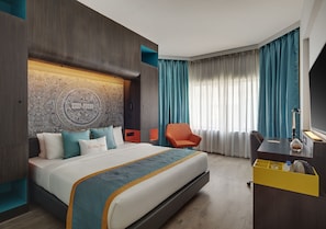 Quarto de hotel com uma cama grande, uma mesa com cadeira, televisão e minibar.