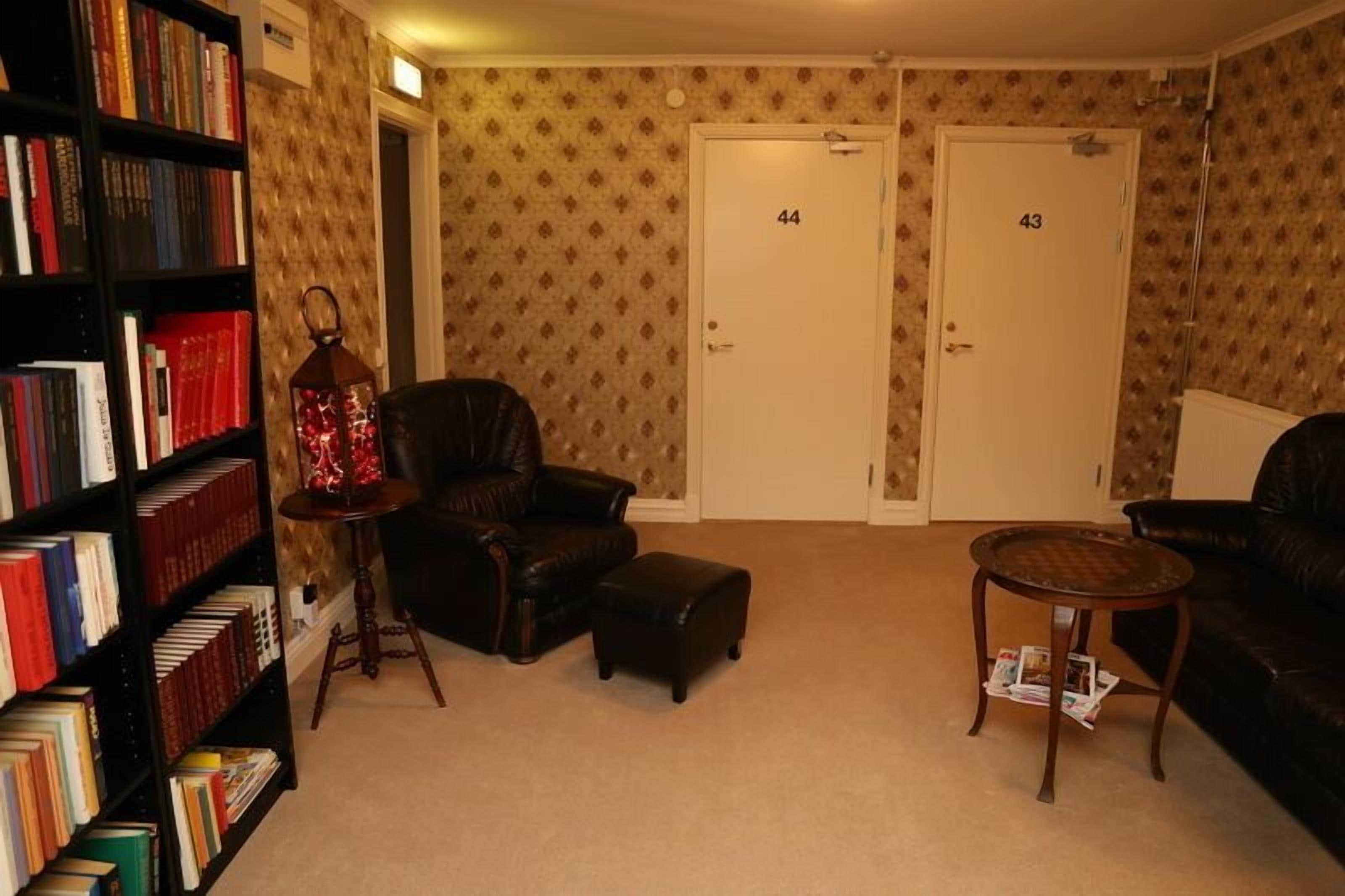 A room with a leather armchair, a small ottoman, a bookshelf, and two doors labeled 44 and 43.