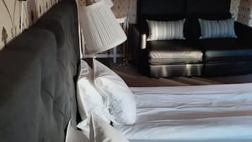Et hotelværelse med en stor seng, en sofa og en lampe.