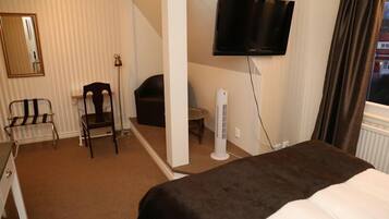 A hotel room with a bed, a chair, a desk, a television, and a window with curtains.