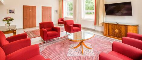 A modern living room with red sofas, a glass coffee table, and a flat-screen TV on a wooden cabinet.