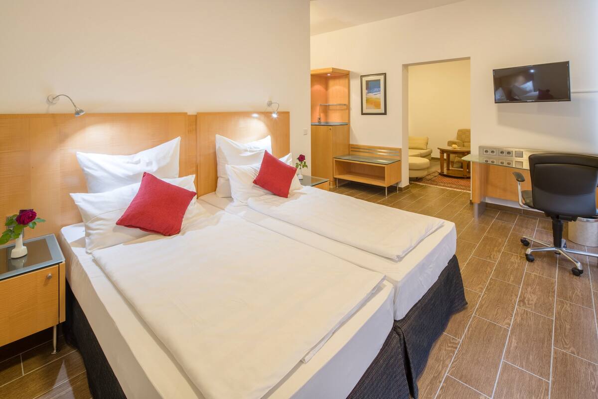 Habitación de hotel con dos camas, un escritorio, una silla, un televisor y un baño.