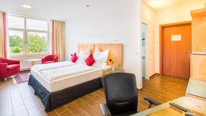 Habitación de hotel con dos camas, un escritorio con teléfono, una silla y una ventana con cortinas.