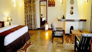 Habitación de hotel con cama, escritorio, silla, espejo y chimenea.