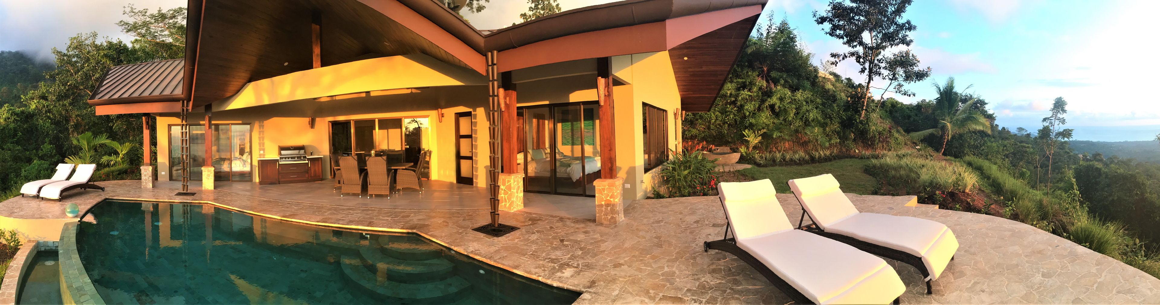 Una casa moderna con piscina, mobiliario exterior y vistas al paisaje circundante.