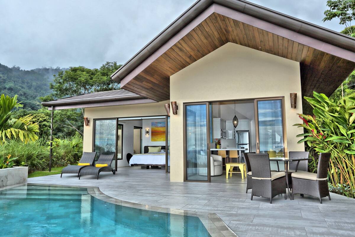 A modern house with a swimming pool, a dining area, and a bedroom with a large window.