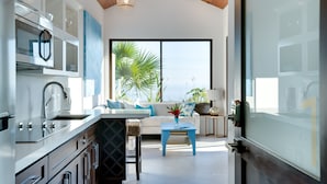A modern kitchen with a dining area, large windows, and a view of the outdoors. - Golden Pineapple Villas (Bahía Ballena)
