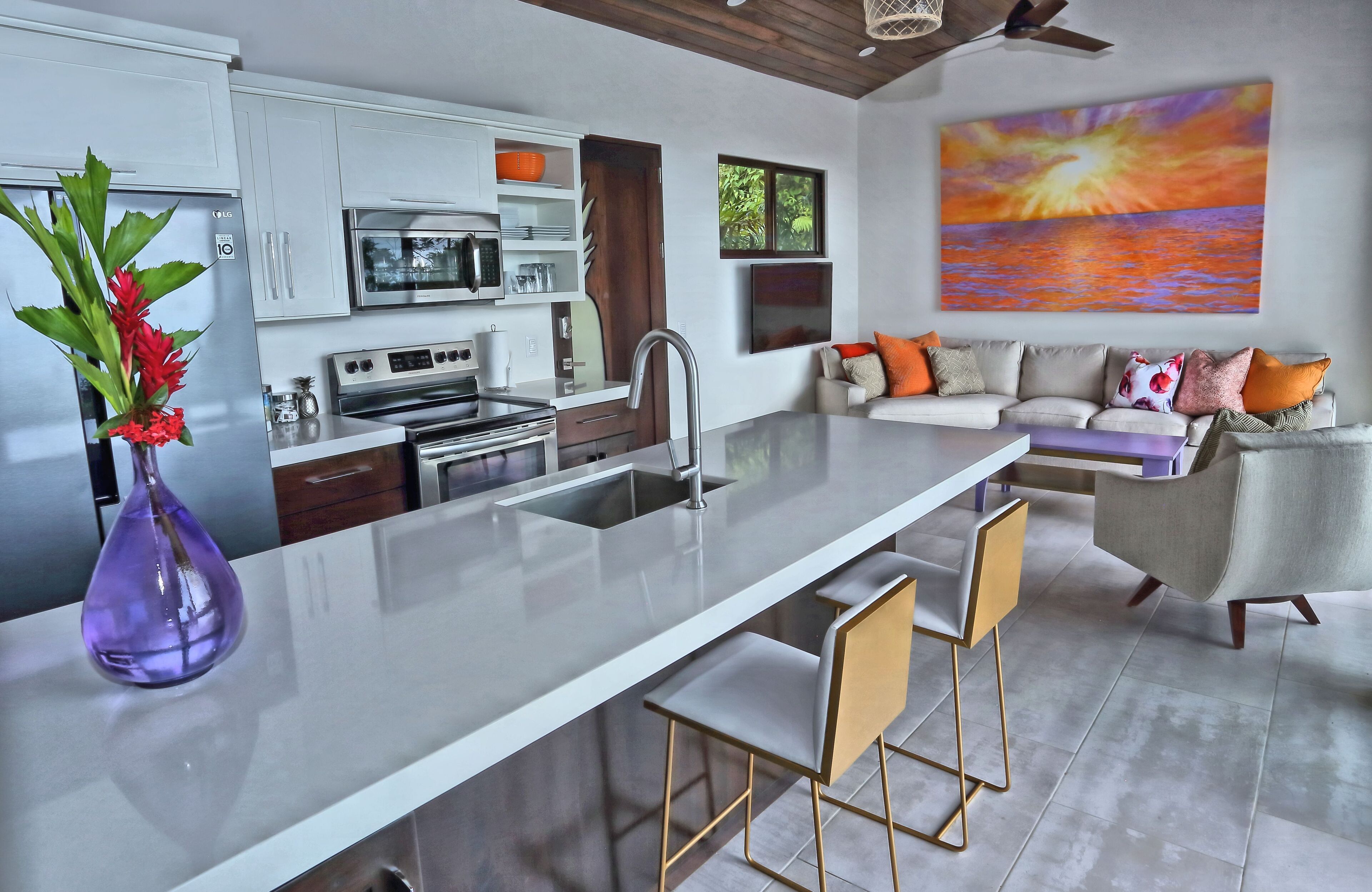 A modern kitchen with a central island, stainless steel appliances, and a dining area with a sofa and chairs.