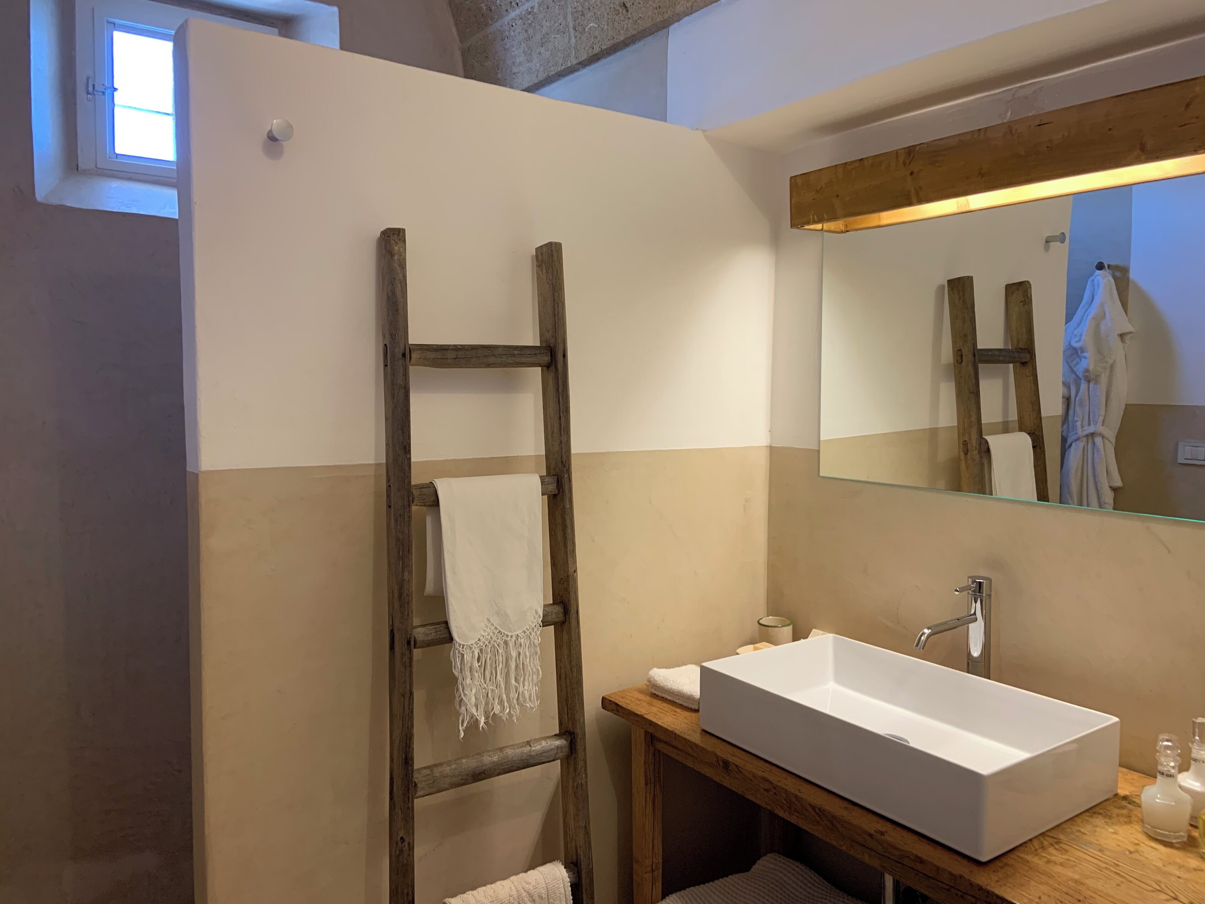 A bathroom with a wooden ladder, a white sink, and a mirror.