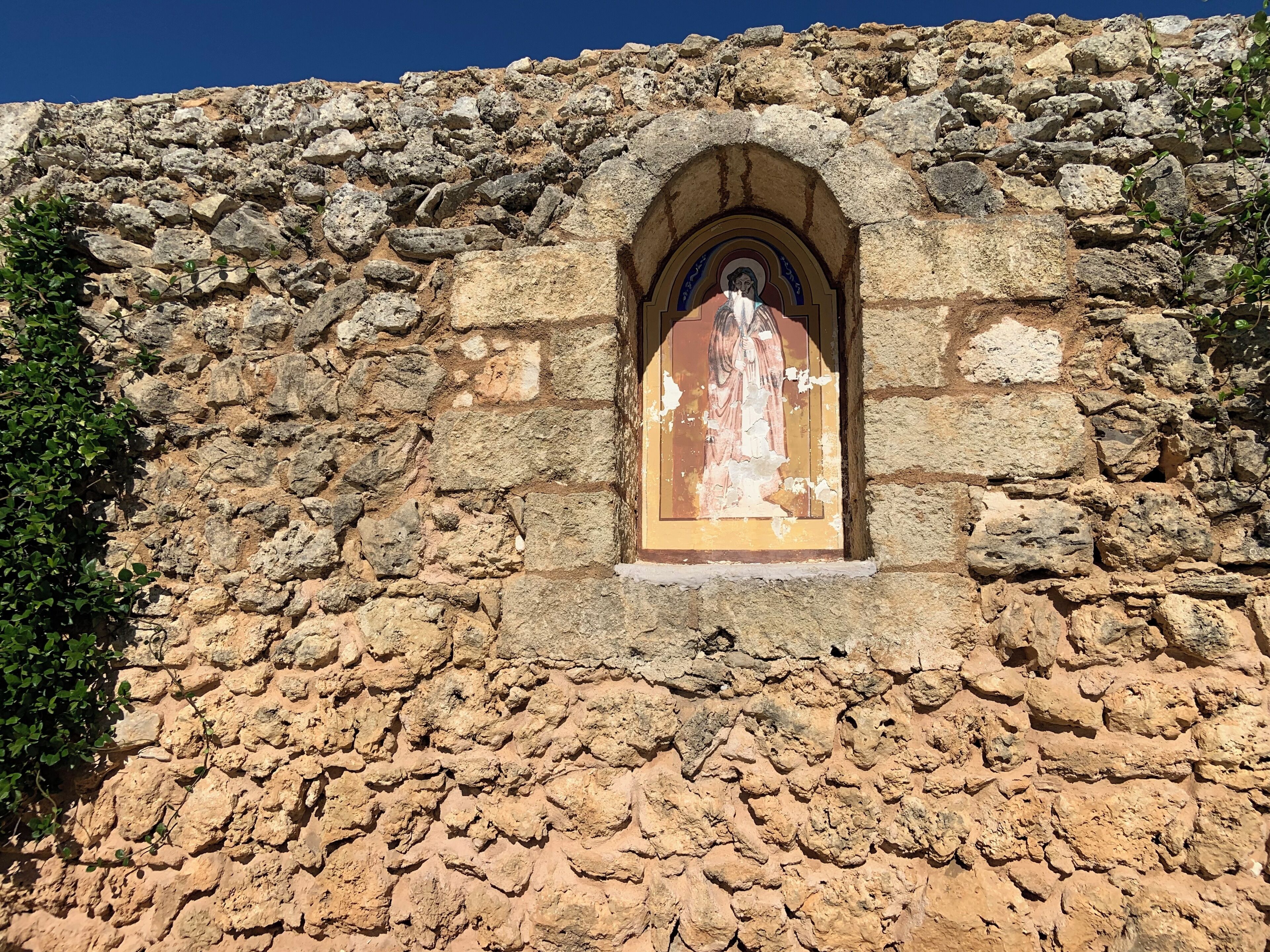 Un muro de piedra con un ícono religioso en un hueco.