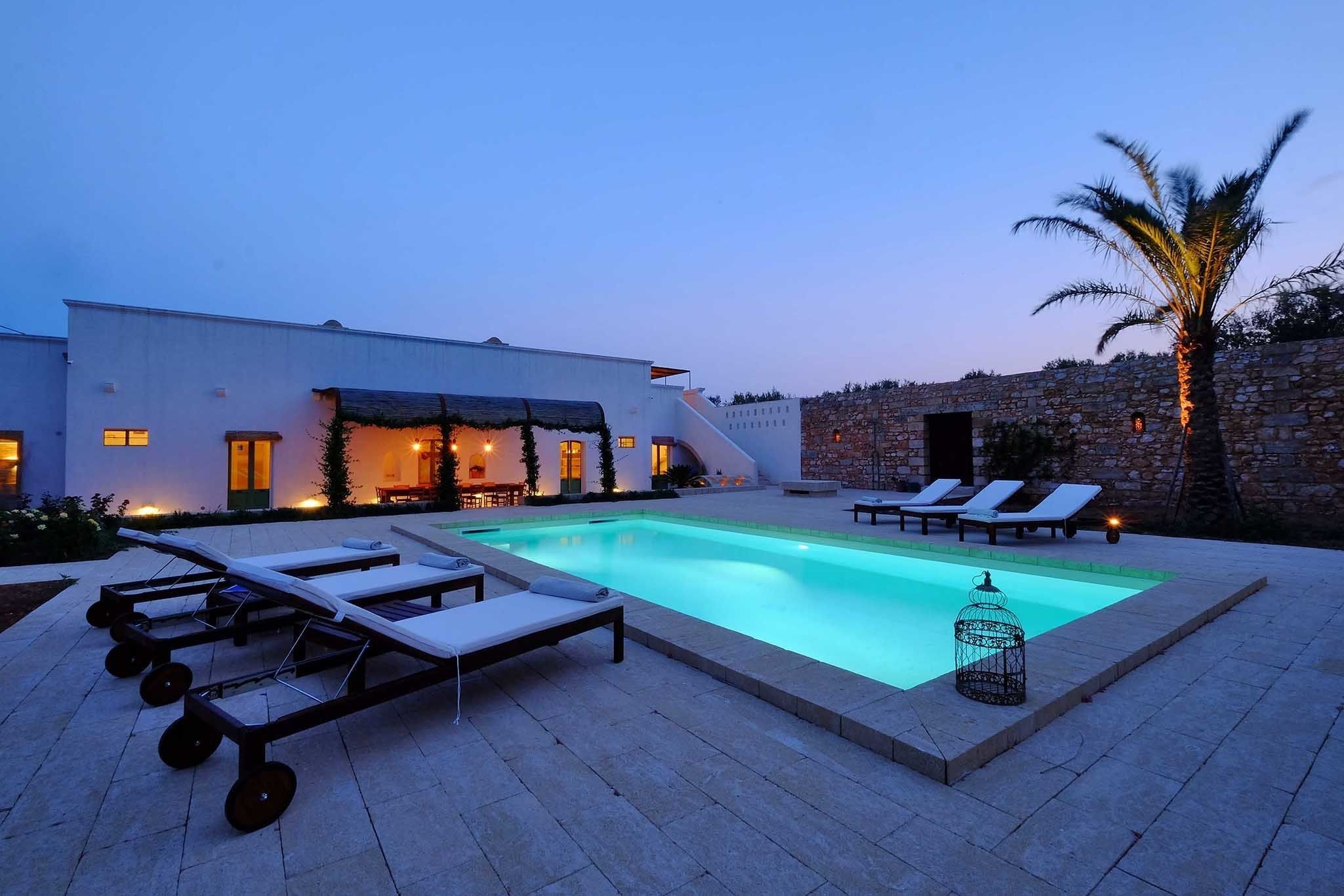 Ein moderner Poolbereich mit Liegestühlen und einer Steinmauer.