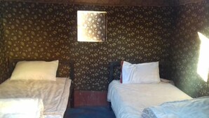 A room with two single beds, a small window, and a floral-patterned wall. - Wadi Rum Accommodation Tour (Wadi Rum)