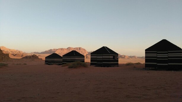 Three striped tents in a desert landscape with mountains in the background. - Wadi Rum Accommodation Tour (Wadi Rum)