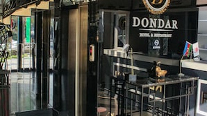 Entrada de hotel con puerta de vidrio, un mostrador de recepción y un letrero que dice "DONDAR HOTEL & RESTAURANT".